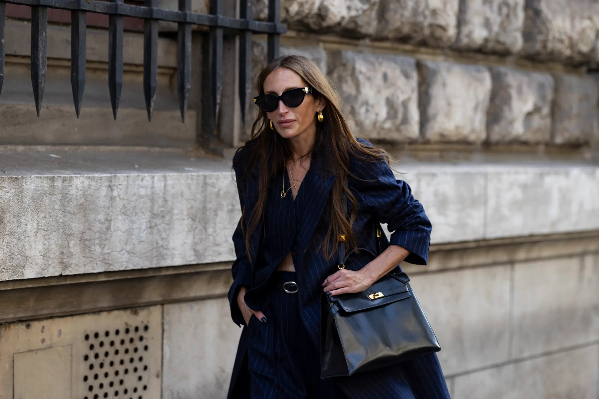 a woman wearing a navy blue striped coat and a hermes kelly bag