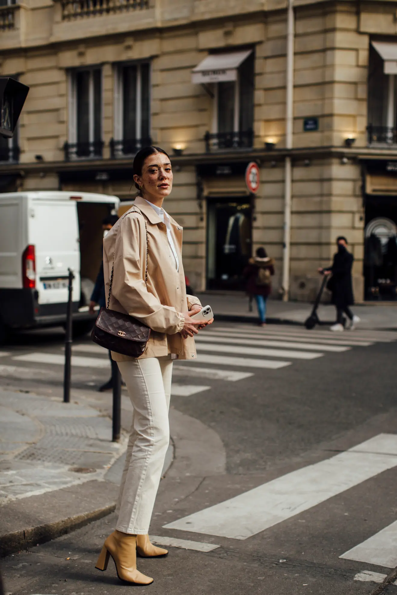 Parisian in the street of Paris with white denim boots and a chanel bag