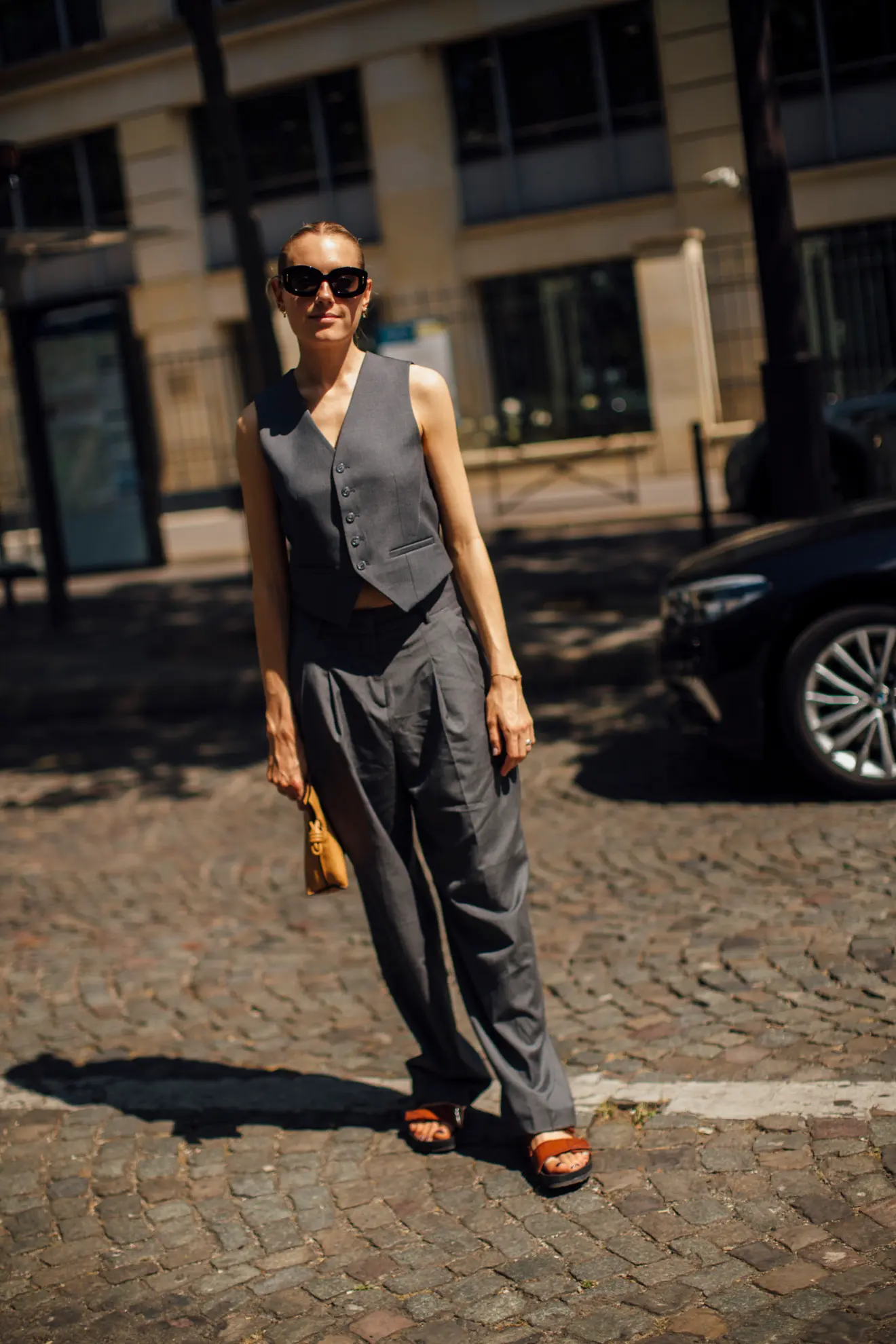 Parisian woman wearing a grey waistcoat and matching trousers with slide sandals 