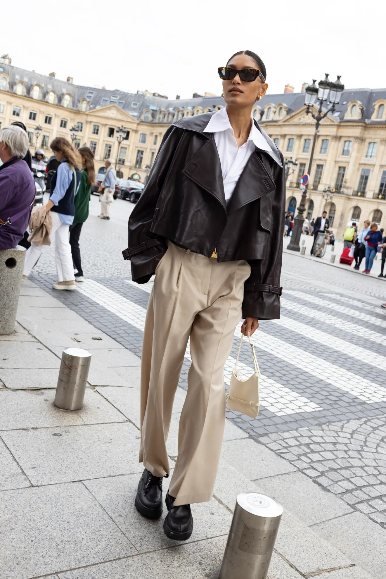 a woman at Paris fashion week street style wearing a cropped leather jacket and beige pleated pants